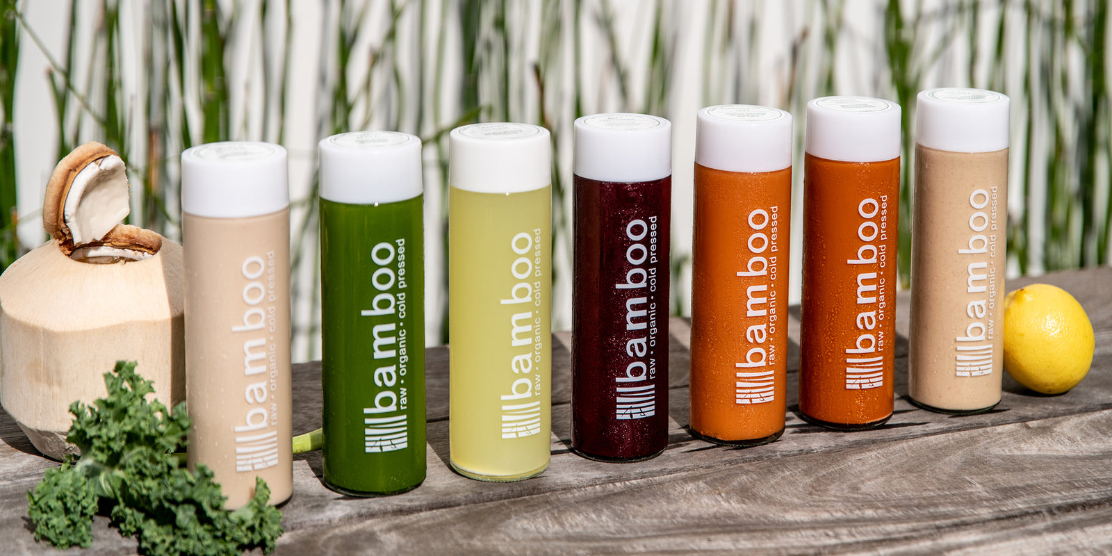 A row of Bamboo Juices cold-pressed bottles in different flavors lined up on a wood surface